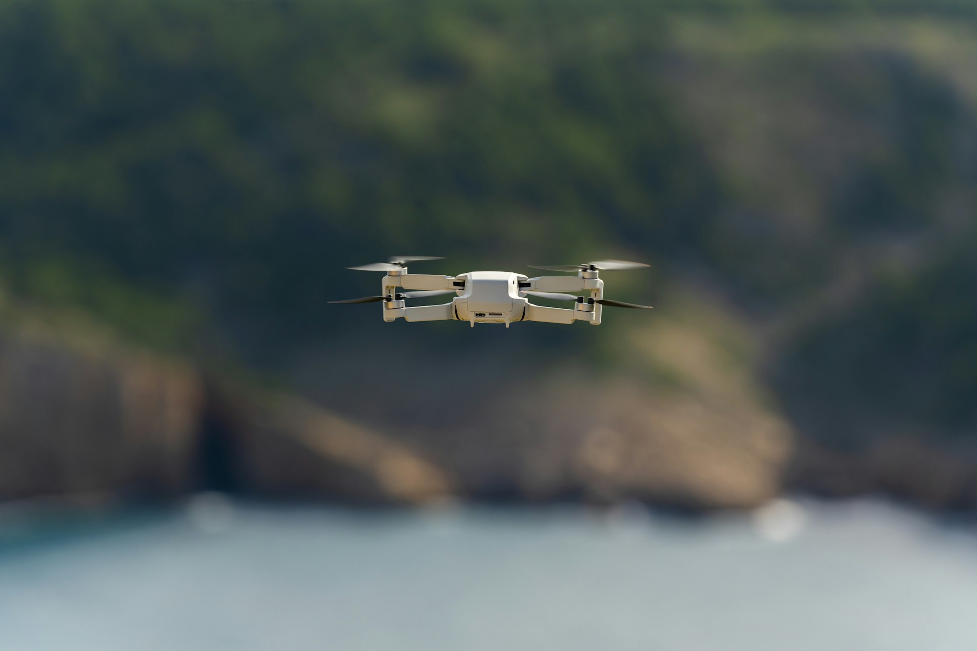 Small drone flying still with a defocused mountain and sea background
