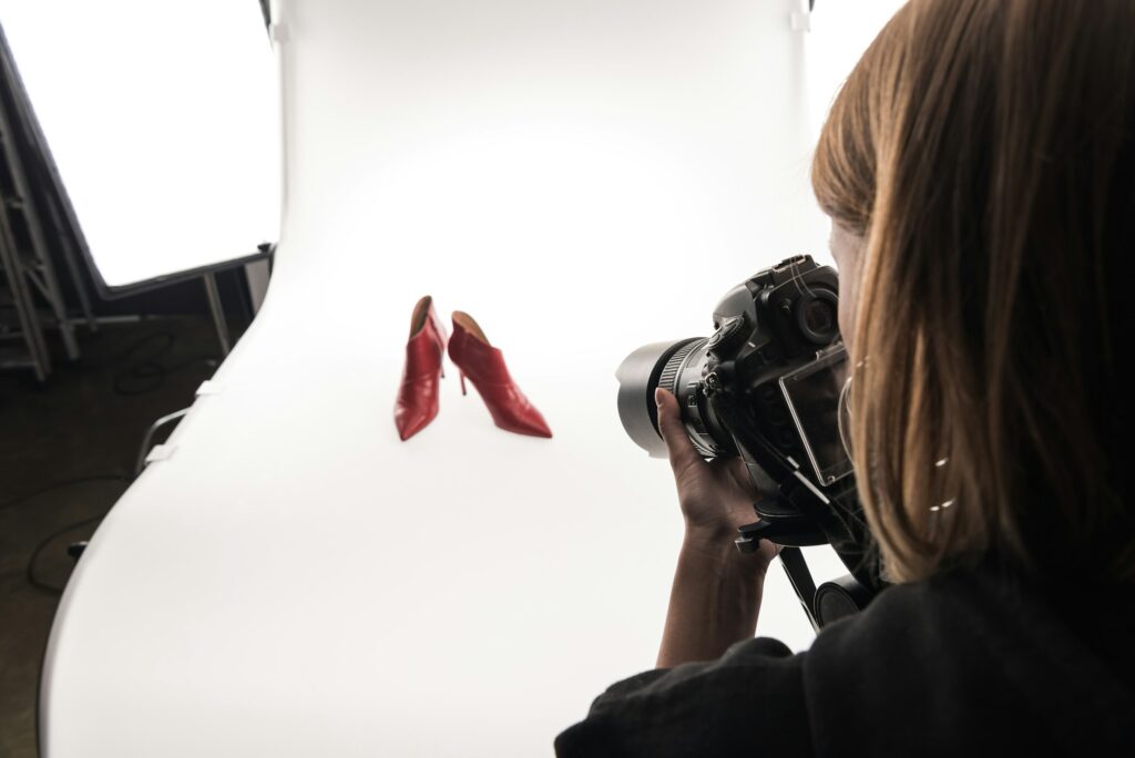 cropped view of commercial photographer making commercial photo shoot of female red heel shoes on